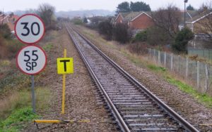 The signs on the left are speed limits - Sprinter Diesel Multiple Units are allowed to proceed at 55 MPH while all other traction is allowed to proceed at 30 MPH. The square yellow sign with the 'T' indicates the end of the temporary speed limit